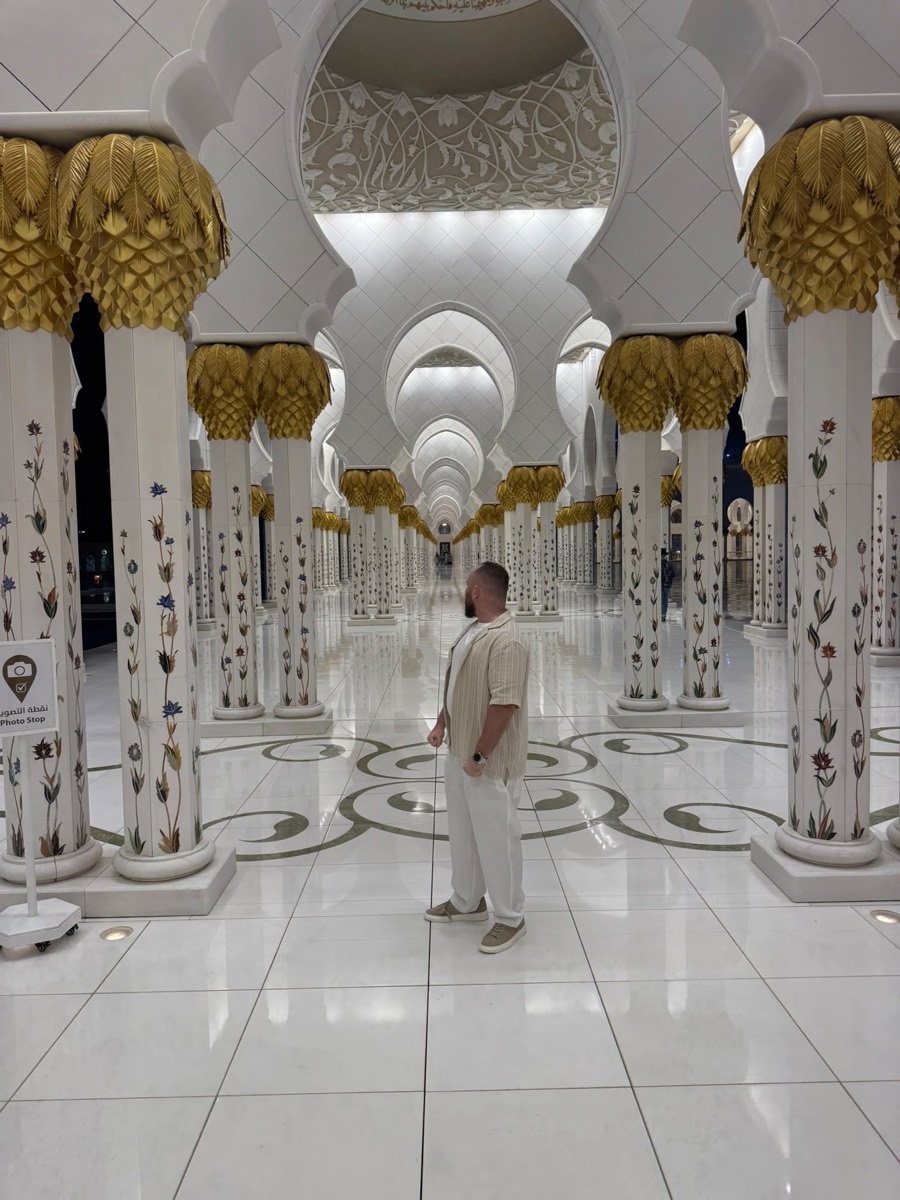 Looking down a corridor of floral marble columns at the Sheikh Zayed Grand Mosque