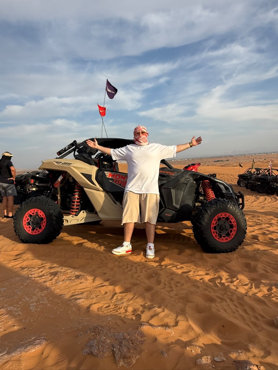 Arms out in front of an off-road buggy on red desert dunes