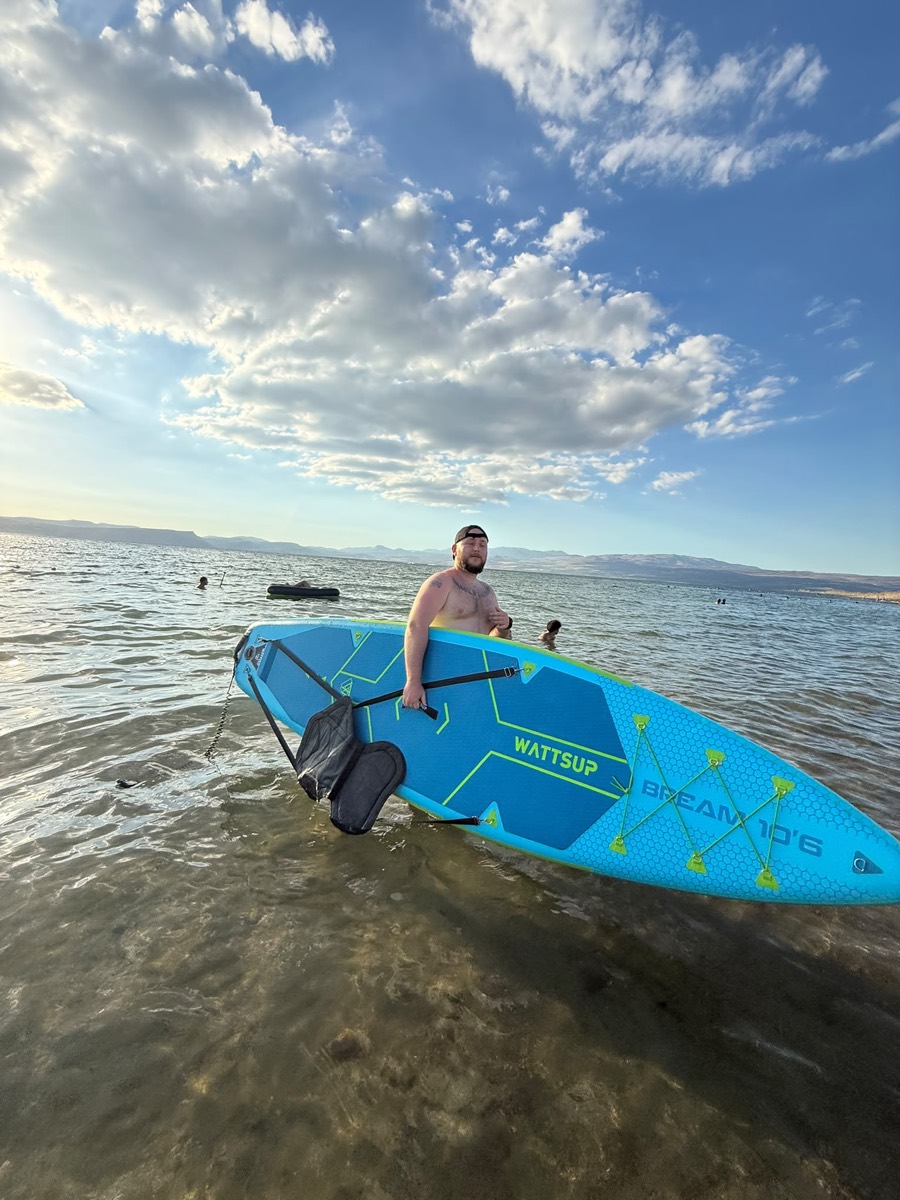 Standing by a paddleboard in clear, shallow sea water